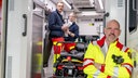 Das Bild zeigt Doc Esser an der Tür eines Krankenwagens lehnend, Im Hintergrund sind zwei Notärtz: innen zu erkennen. 