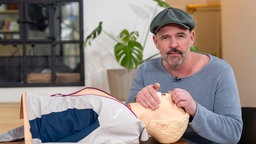 Doc Esser führt an einer Reanimationspuppe vor, wie man eine Mund-zu-Mundbeatmung durchführt.