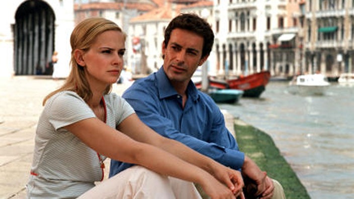 Mann und Frau sitzen in Venedig am Canale Grande