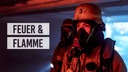 Feuerwehrmänner vor einer brennenden Wand