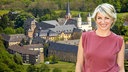 Sabine Heinrich lächelt in die Kamera, hinter eine Burg