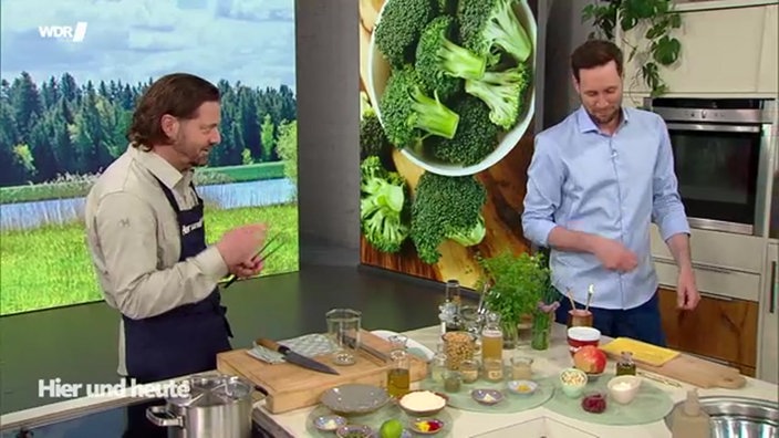 Olaf Baumeister und Modertor Sven Kroll stehen an der Küchenzeile im Hier und Heute Studio während sie kochen
