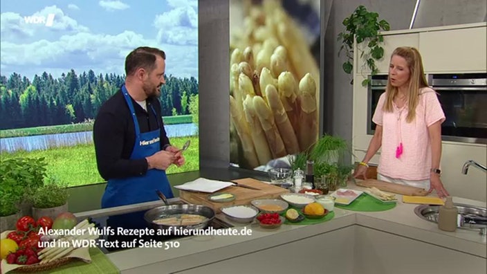 Alexander Wulf steht mit Moderatorin Miriam Lange an der Küchenzeile im Hier und Heute Stduio während sie kochen