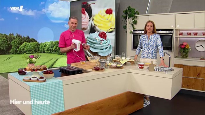 Aufnahme von Matthias Ludwigs mit Mixer in der Hand und Miriam Lange in der Küche beim Backen.