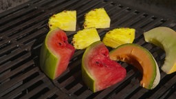 Das Bild zeigt Ananas, Wassermelone und Honigmelone auf dem Grill.
