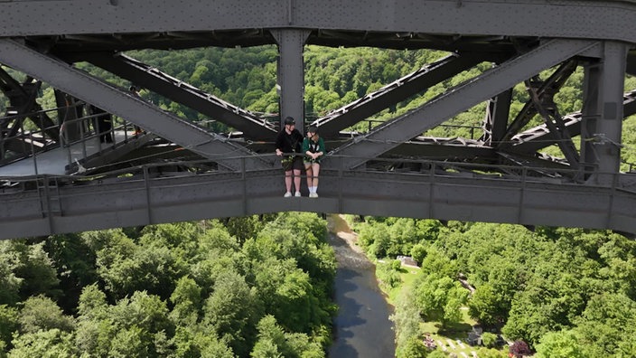 Das Bild zeigt zwei Personen auf einer großen Brücke.