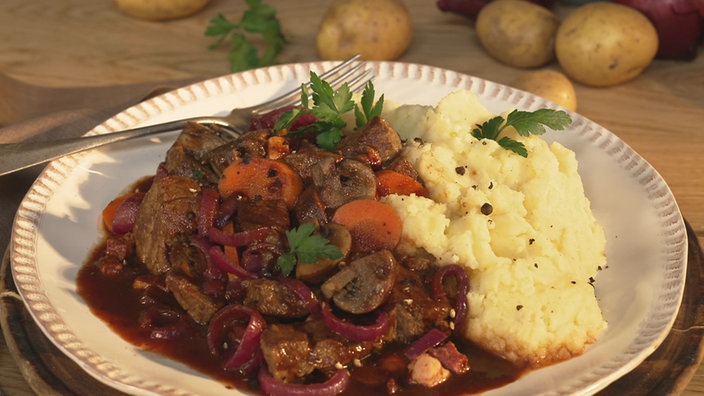Auf einem Teller ist das Boeuf Bourguignon serviert mit dem Sellerie-Kartoffelstampf.