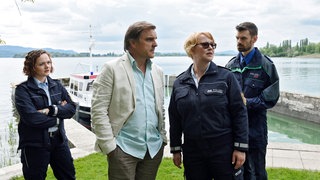 Kommisare diskutieren am Hafen.