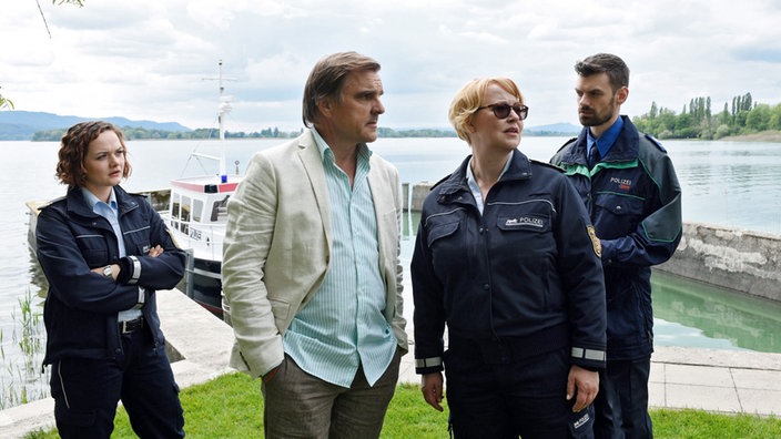 Kommisare diskutieren am Hafen.
