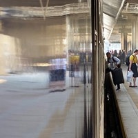 Menschen in der Ferne, die aus einem Zug am Bahnhof ein- und aussteigen.