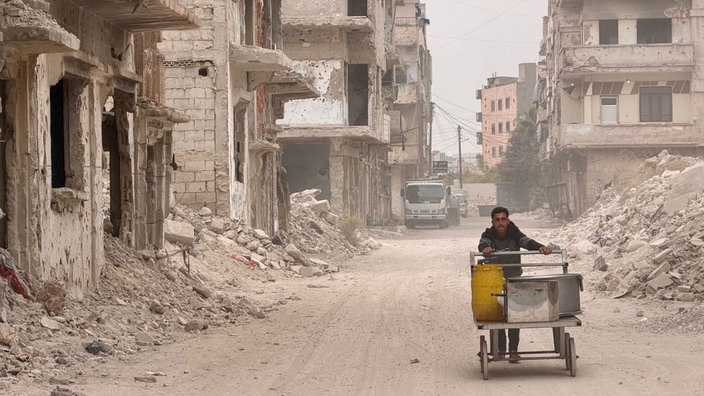 Ein Maisverkäufer im zerstörten Stadtviertel El Khaldiyye in Homs, unterwegs zwischen den Trümmern.