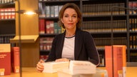 Anna Planken an einem Tisch, vor ihr liegen verschiedene Bücher.