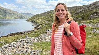 Tamina Kallert steht vor einer Schlucht in Irland. Sie lächelt in die Kamera.