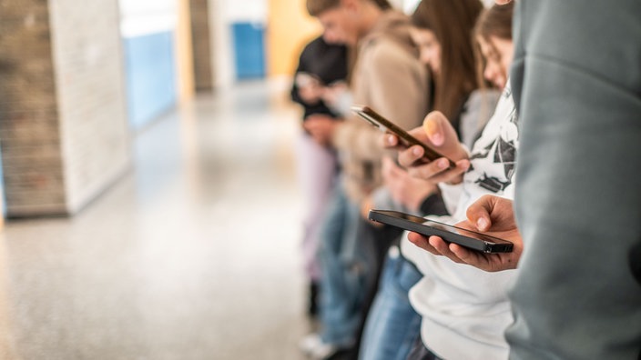 Jugendliche in der Schule halten Handys in den Händen 