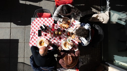 Vier Personen essen an einem Tisch.