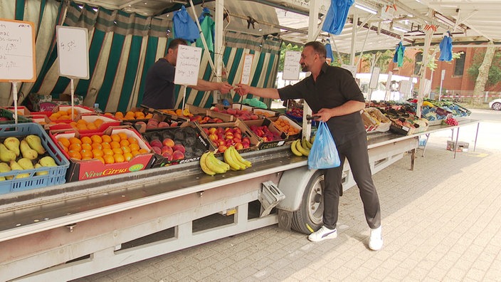 Mirze Edis (Linke Duisburg) bezahlt an einem Marktstand