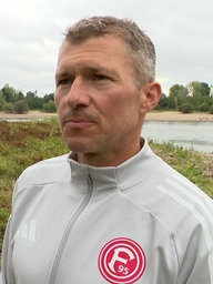 Ein Mann in einer grauen Sportjacke im Interview