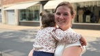 Junge Frau mit Kind auf dem Arm schaut in die Kamera