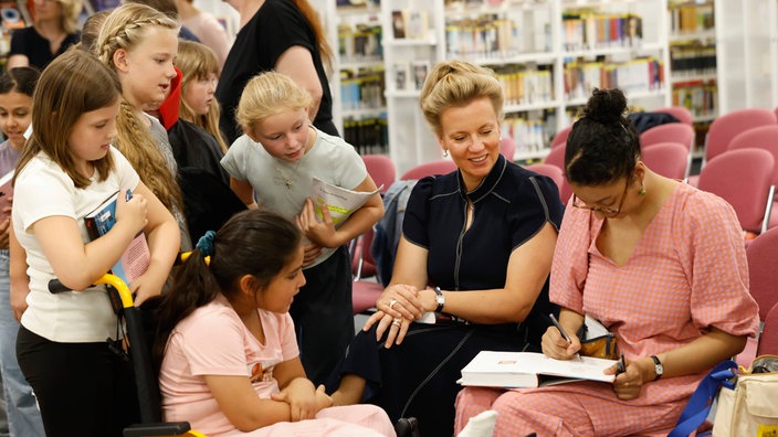 Kinderbuchautorin unterschreibt neben Kindern ihr eigenes Buch