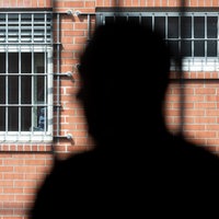 Insasse steht vor einem vergitterten Fenster in der Unterbringungseinrichtung für Ausreisepflichtige (UfA).