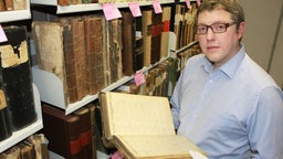 Ahnenforscher C. A. Hoske hält ein altes Buch 