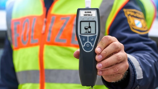 Polizist hält Gerät zur Alkoholkontrolle in der Hand