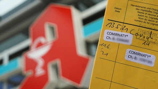 Ein Impfpass vor einer Apotheke