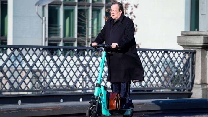 Armin Laschet fährt auf einem E-Scooter.