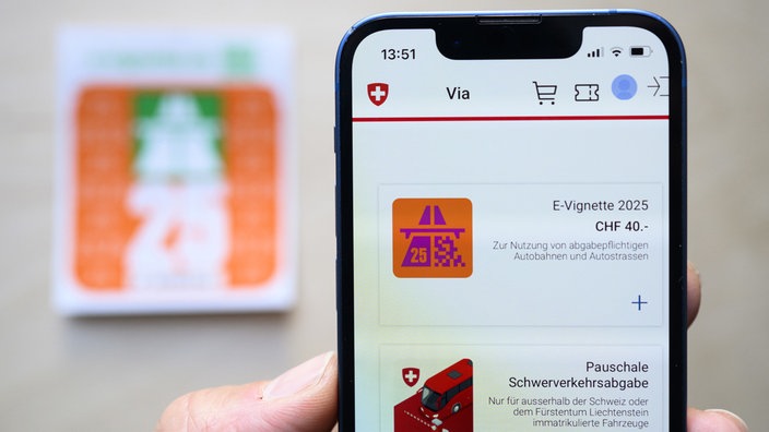 Eine Hand hält ein Smartphone mit schweizer E-Vignette ins Bild