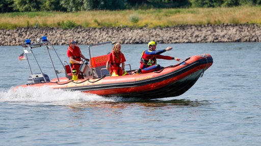 Einsatzkräfte der Berufsfeuerwehr Köln, der DLRG und Rettungstaucher auf einem Schlauchboot im Rhein