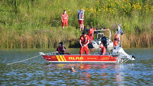 Einsatzfahrzeuge der Polizei und Feuerwehr auf einem See