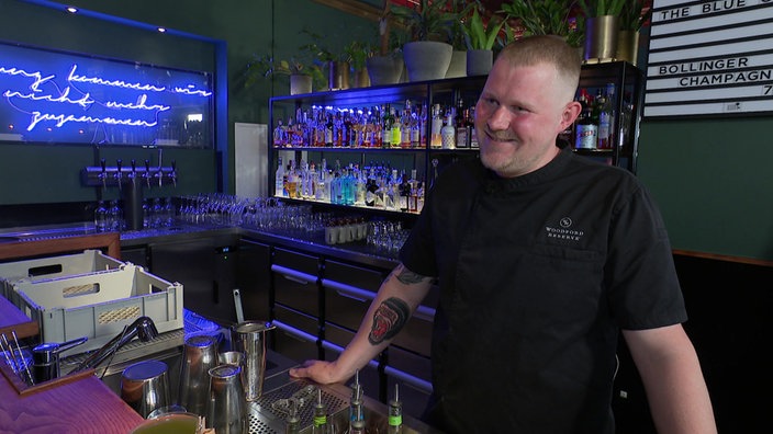 Ein Barkeeper steht hinter der Theke einer Bar