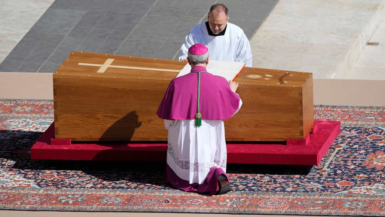 Erzbischof Diego Giovanni Ravelli, mit dem Rücken zur Kamera, kniet neben dem Sarg von Papst Franziskus auf dem Petersplatz