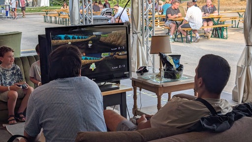 Zwei Junge Männer zocken Mario Kart auf einem Bildschirm