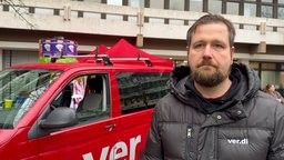 Björn Jadzinski steht vor einem Auto der Gewerkschaft Ver.di