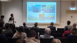Einige Menschen hören sich in Siegen einen Vortrag an und betrachteten eine Präsentation