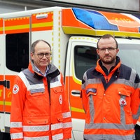 Christoph Schlütermann und Sven Nolte stehen vor einem Rettungswagen der Wache Coesfeld