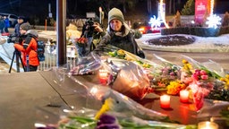 Eine Frau legt Blumen in der Nähe der Stelle nieder, an der am 1. Januar 2026 in Crans-Montana ein Feuer in einer überfüllten Bar ausgebrochen war. 