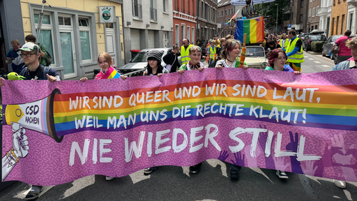 Demonstrierende beim CSD in Aachen mit buntem Banner