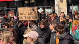 Ein Schild "Die Scham muss die Seite wechseln" wird bei einer Demo hochgehalten