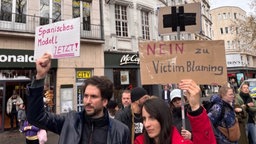 Zwei Menschen halten Schilder hoch zu Vorderungen zum Fall Fernandes