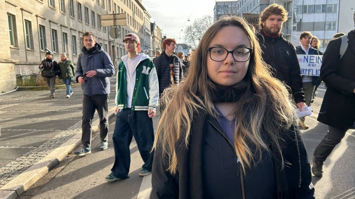 Eine junge Frau mit dunkler Brille und langen braunen Haaren in Bonn