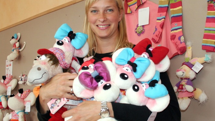 Blonde Frau mittleren Alters mit den Armen voller Kuscheltiere
