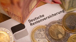 Ein Schreiben der Deutschen Rentenversicherung liegt zwischen Euro-Banknoten und mehreren Euromünzen.