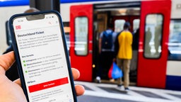 Am Bahnhof zeigt eine Person ihr Deutschlandticket auf dem Display eines Smartphones 