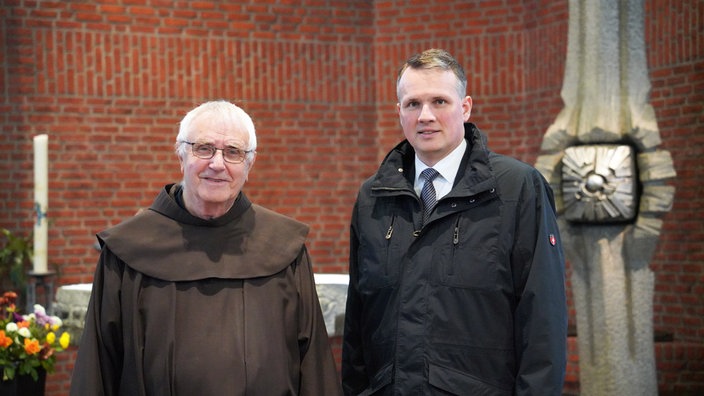 Pater Heribert und Bürgermeister Tobias Stockhoff stehen vor dem Altar der Klosterkirche 