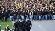 Menschenmenge aus Dortmund-Fans läuft hinter Polizei 
