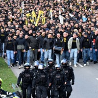 Menschenmenge aus Dortmund-Fans läuft hinter Polizei 