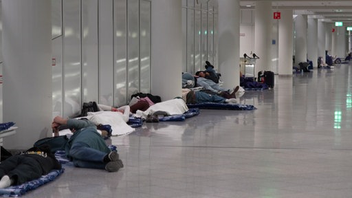 Menschen ruhen sich nach möglichen Drohnensichtungen am Flughafen München aus