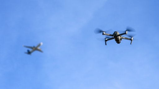 Eine Drohne fliegt vor einem startenden Flugzeug in der Nähe des Flughafens Leipzig/Halle